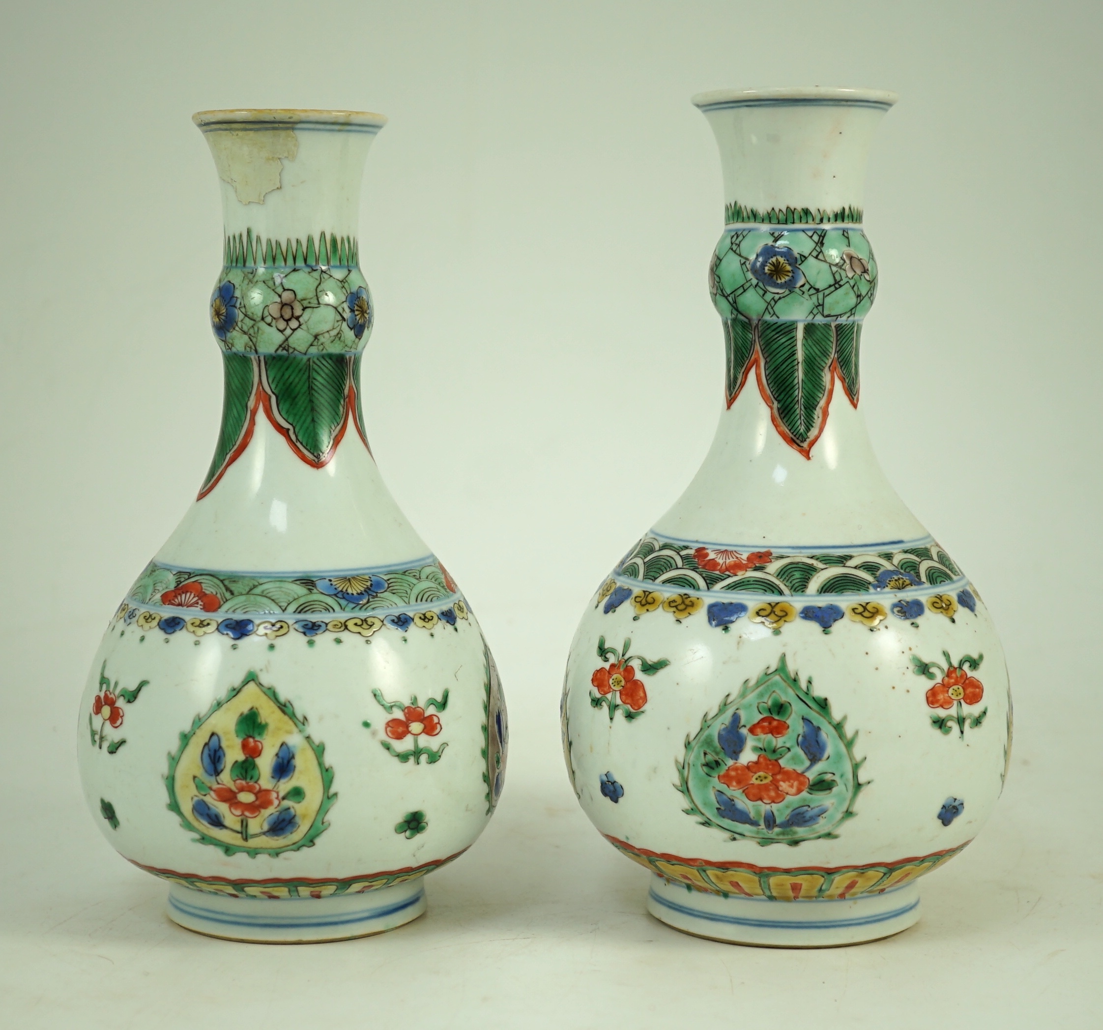 A near pair of Chinese famille verte garlic-neck vases, Kangxi period, 20cm and 20.5cm high, One vase restored